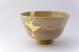 Photo of gray colored Kintsugi vase, with lots of golden healing cracks.